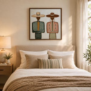 May include: A square framed wall art piece featuring a stylized illustration of two figures wearing wide-brimmed hats. The figure on the left wears a blue and yellow striped garment, while the figure on the right wears a pink and white patterned top.