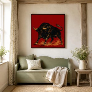 May include: A square wall art print featuring a detailed black bull illustration against a solid red background. The bull is depicted in a charging stance with golden-toned horns and hooves, with stylized orange dust clouds swirling beneath its feet.