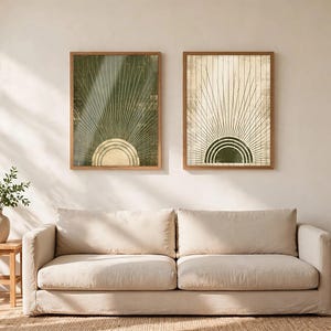 May include: Two rectangular framed wall art prints featuring a sunburst motif. The left print has a dark green background with a light-colored semi-circle, while the right print has a light background with a dark green semi-circle.