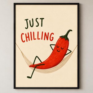 May include: A framed wall art print featuring a red chili pepper with a smiling face relaxing in a beige hammock. The text "JUST CHILLING" is printed in dark green and red letters above the chili pepper against a light cream background.