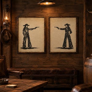 K&ouml;nnte beinhalten: Zwei gerahmte Wandbilder mit schwarzen Tuschezeichnungen einer Cowgirl-Figur mit Hut und Fransenhose, die einen Revolver h&auml;lt. Die Drucke befinden sich auf einem hellbeigen Hintergrund und sind in dunkle Holzrahmen gefasst, nebeneinander platziert.