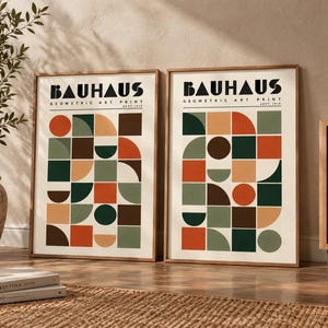 K&ouml;nnte beinhalten: Zwei gerahmte Kunstdrucke mit dem Text BAUHAUS GEOMETRIC ART PRINT SEPT 1919. Jeder Druck zeigt ein Raster aus geometrischen Formen wie Kreisen, Halbkreisen und Quadraten in einer Farbpalette aus Dunkelgr&uuml;n, gebranntem Orange, Braun und Beige.