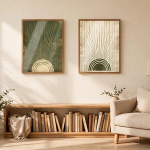 May include: Two rectangular wall art prints in wooden frames. The left print features a dark green background with a gold sunburst design. The right print features a cream background with a dark green sunburst design. Both display radiating lines.