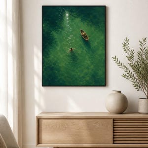 May include: A rectangular wall art print featuring an aerial view of a small wooden rowboat floating on vibrant green water. A person is swimming in the clear water near the boat, with sunlight reflecting off the surface of the deep green sea.