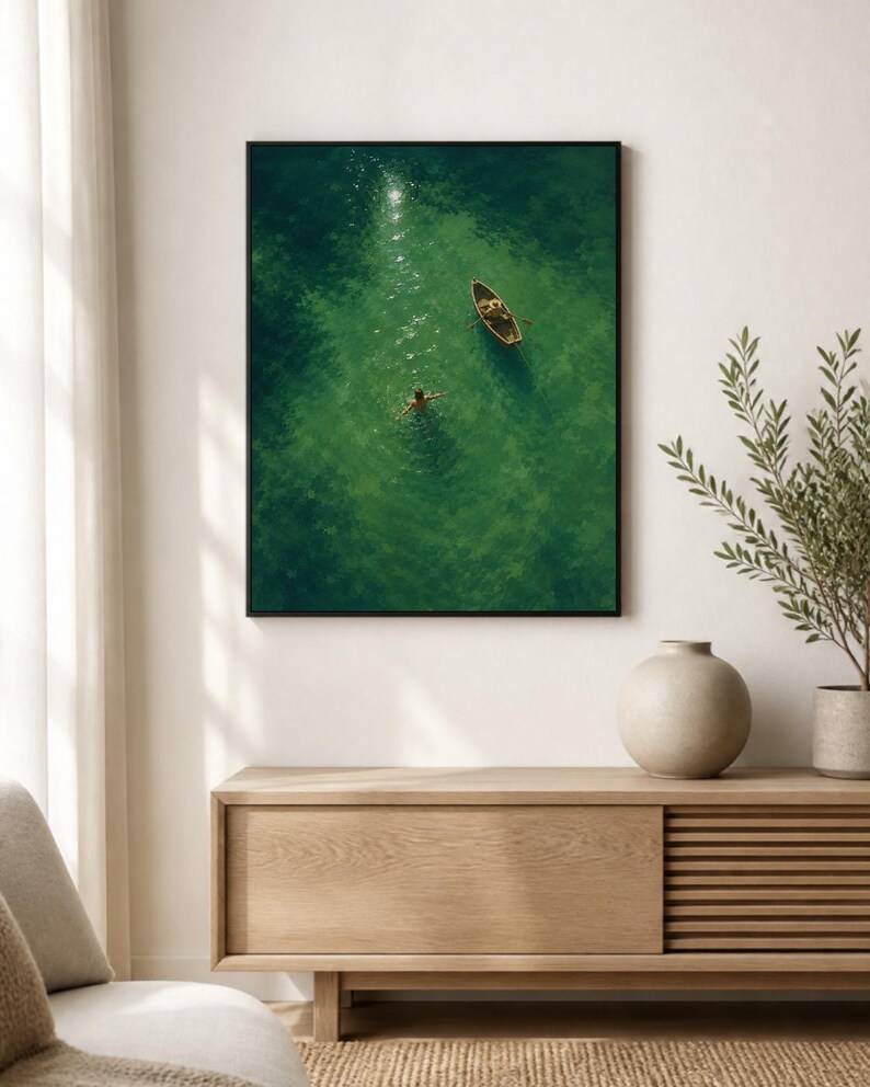 May include: A rectangular wall art print featuring an aerial view of a small wooden rowboat floating on vibrant green water. A person is swimming in the clear water near the boat, with sunlight reflecting off the surface of the deep green sea.