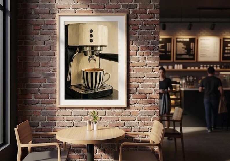 May include: A framed wall art print depicting a cream and black espresso machine brewing coffee into a black and white striped ceramic mug. The machine features a metallic portafilter, three circular buttons, and a steam wand, all set against a neutral background.