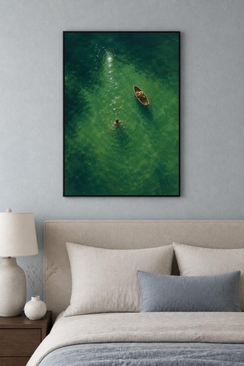 May include: A framed wall art print featuring an aerial view of a small wooden rowboat floating on vibrant green water. A person is swimming in the clear, sunlit water near the boat, creating gentle ripples. The artwork is enclosed in a black frame.