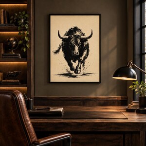 K&ouml;nnte beinhalten: Ein gerahmter Wandkunstdruck mit einer schwarzen Tuscheillustration eines st&uuml;rmenden Stiers auf cremefarbenem Hintergrund. Das Kunstwerk zeigt den Stier in einer dynamischen Vorw&auml;rtsbewegung mit sichtbaren Pinselstrichstrukturen.