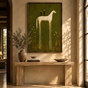May include: A rectangular wall art print featuring a stylized white horse with elongated legs standing on a dark olive green background. Two small black figures with wide-brimmed hats stand on the horse's back. Thin white flowers grow below.