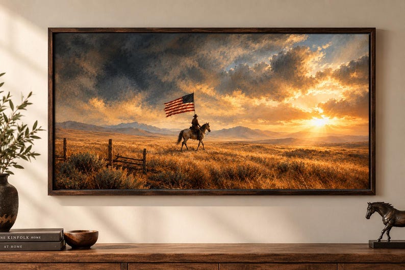 May include: A rectangular framed wall art print depicting a lone rider on horseback carrying an American flag across a golden prairie landscape at sunset. The scene features distant mountains, a wooden fence, and a dramatic sky with clouds.