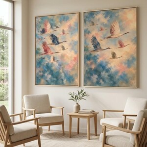 May include: Two rectangular wall art pieces in light wood frames featuring oil-style paintings of cranes in flight against a backdrop of blended blue, pink, and cream clouds. The artwork displays multiple birds with wings spread in various positions.