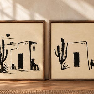 May include: Two framed wall art prints featuring black ink illustrations on a beige background. The left print shows a cactus, a barrel, a building with a lantern, and a seated figure in a hat. The right print shows a cactus and a seated figure.