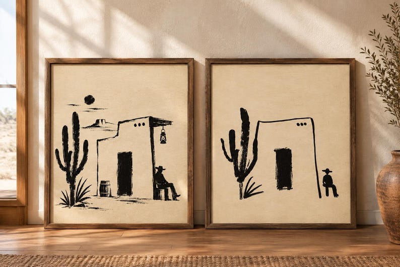 May include: Two framed wall art prints featuring black ink illustrations on a beige background. The left print shows a cactus, a barrel, a building with a lantern, and a seated figure in a hat. The right print shows a cactus and a seated figure.