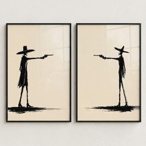 May include: Two framed wall art prints featuring black ink-style silhouettes of figures wearing wide-brimmed hats and long coats. Each figure stands in profile, pointing a handgun towards the other, set against a solid light beige background.
