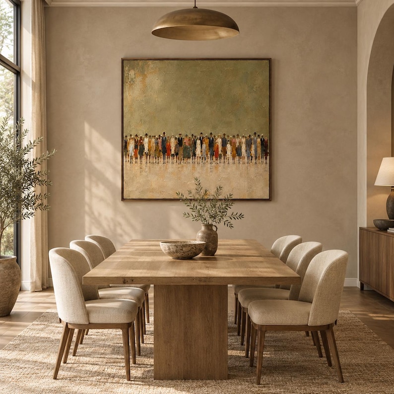 May include: A large square wall art piece featuring an abstract painting of a crowd of people in muted tones of brown, blue, and orange against a textured sage green background, framed in a thin dark wood border and displayed above a dining table.