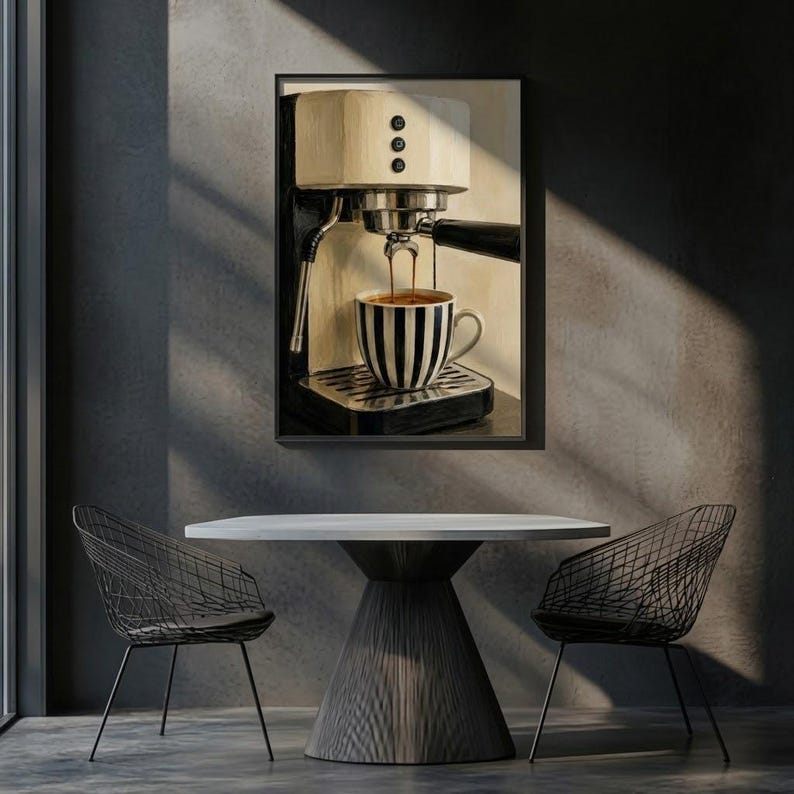 May include: A framed wall art print depicting a cream-colored espresso machine brewing coffee into a black and white vertically striped ceramic mug. The machine features a black portafilter, a metallic drip tray, and three circular control buttons.