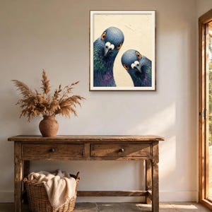 May include: A framed wall art print featuring two pigeons with iridescent blue and purple neck feathers and orange eyes, set against a cream-coloured background. The birds are positioned close together, looking directly forward at the viewer.