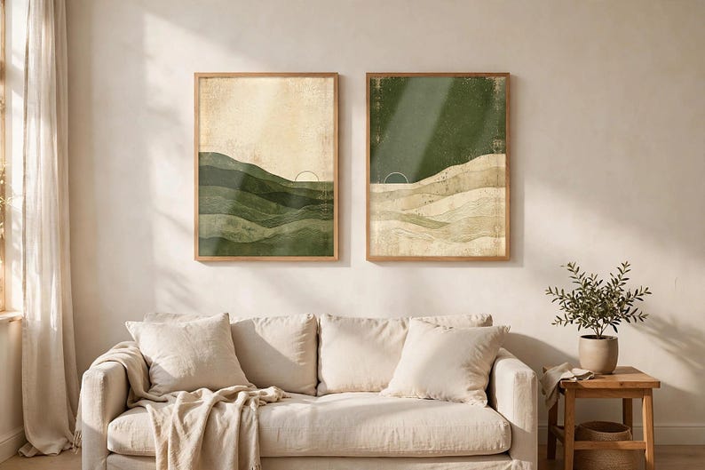 May include: Two rectangular framed wall art prints featuring abstract landscape designs. The left print displays layered green hills against a cream sky, while the right print shows layered cream hills against a dark green sky, both with a thin sun arc.