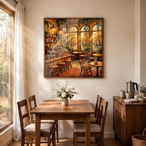 May include: A square wall art print depicting a cozy cafe interior with warm golden lighting, wooden furniture, a coffee bar, and large arched windows. The scene features small round tables, wooden stools, hanging plants, and a cat resting on a chair.