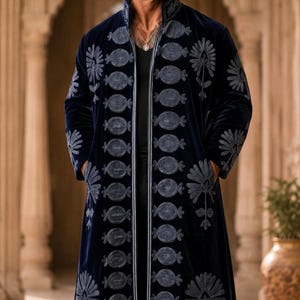 May include: A long, dark blue velvet coat featuring a high collar and vertical rows of circular embroidery along the front opening. The garment is adorned with large, stylized floral patterns in a lighter blue thread on the chest and sleeves.