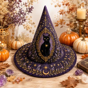 May include: A pointed purple hat featuring intricate gold embroidery of a black cat centered within an ornate frame. The fabric is decorated with gold stars, crescent moons, and botanical patterns. The design covers the conical crown and wide brim.