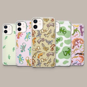 Op de afbeelding: Vijf doorzichtige smartphonehoesjes met diverse hagedis- en gekkopatronen. De ontwerpen bevatten kleine groene hagedissen op lichtgroen, kleurrijke gekko's op lichtroze, luipaardgekko's op beige, groene hagedissen op een witte koeienprint en gemengde hagedissen op lavendel.