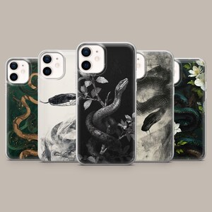 Puede incluir: Cinco fundas transparentes para smartphone con diversas ilustraciones de serpientes. Los diseños incluyen una serpiente marrón sobre fondo verde oscuro, una serpiente en blanco y negro, una serpiente enroscada sobre fondo oscuro, una serpiente gris y una serpiente con flores blancas.