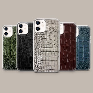 Könnte beinhalten: Fünf Smartphone-Hüllen in einer Reihe, jede mit einer ausgeprägten Krokodilleder-Textur. Die Farben von links nach rechts sind Olivgrün, Schwarz, Metallic-Silber, Dunkelbraun und Dunkelblau, alle mit einem Ausschnitt für die Doppelkamera.