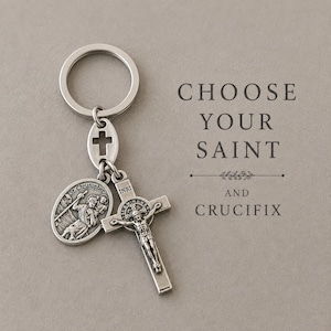 Puede incluir: Un llavero de metal plateado con una anilla circular, una medalla ovalada de San Cristóbal y un crucifijo con la inscripción INRI. El texto CHOOSE YOUR SAINT AND CRUCIFIX está impreso a la derecha de los dijes religiosos.