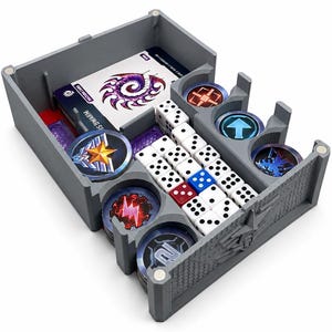 Könnte beinhalten: Ein grauer, 3D-gedruckter Spiele-Organizer mit magnetischen Ecken, der ein Kartendeck mit violetter Spiralgrafik, mehrere Stapel runder Spielmarken mit verschiedenen Symbolen sowie eine Sammlung weißer, blauer und roter sechsseitiger Würfel enthält.