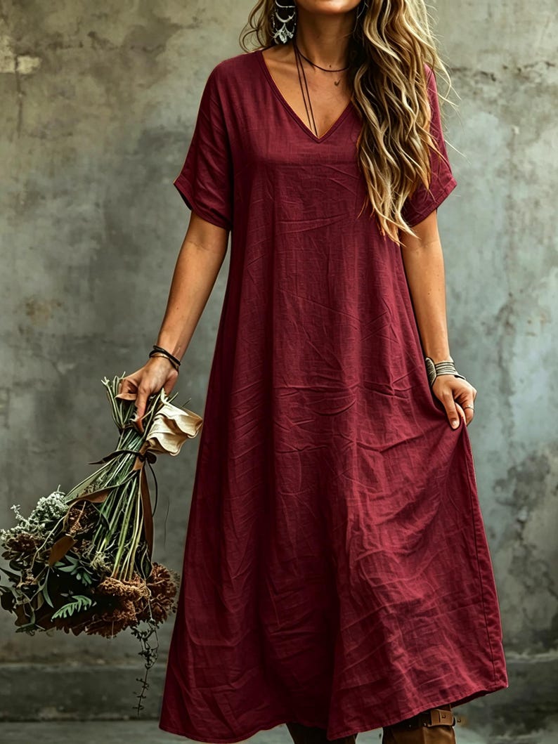 K&ouml;nnte beinhalten: Ein tiefburgunderrotes Midikleid mit V-Ausschnitt und kurzen &Auml;rmeln. Das Kleidungsst&uuml;ck hat eine lockere, weit geschnittene Silhouette mit einer strukturierten Stoffoberfl&auml;che. Das Kleid ist in einem einfarbigen Dunkelrot gehalten.