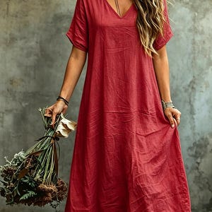 K&ouml;nnte beinhalten: Ein einfarbiges rotes Maxikleid mit V-Ausschnitt, kurzen &Auml;rmeln und einer lockeren, flie&szlig;enden Silhouette. Das Kleidungsst&uuml;ck hat eine strukturierte Optik und reicht bis zu den Unterschenkeln, was eine entspannte Passform mit schlichtem Design bietet.