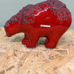 Peut inclure: Une figurine d'ours en céramique avec un vernis rouge vif et une finition texturée gris foncé semblable à de la lave sur le dos et la tête. Le côté de l'ours présente une petite étiquette rectangulaire blanche avec le texte OTOKERAMIK.