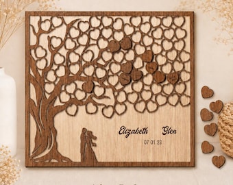 May include: A square wooden guest book featuring a laser-cut tree with numerous heart-shaped leaves. A couple silhouette stands at the base. The text reads Elizabeth, Glen, and 07 01 23. Several loose wooden hearts are placed to the right side.