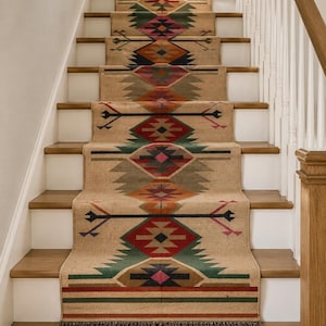 May include: A long stair runner rug featuring a tan base with a repeating geometric pattern in red, green, orange, black, and pink. The runner has a fringed edge at the bottom and is installed over wooden stairs with white risers and a wooden railing.