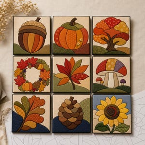 May include: A set of nine square fabric panels featuring quilted autumn motifs including an acorn, pumpkin, tree, wreath, leaf, mushroom, oak leaf, pinecone, and sunflower, all rendered in warm seasonal colors on a light background.