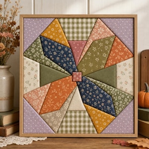 May include: A square fabric wall art piece featuring a geometric star pattern composed of various cotton patches in shades of mustard yellow, navy blue, olive green, burnt orange, and cream, all set within a light-toned wooden frame.