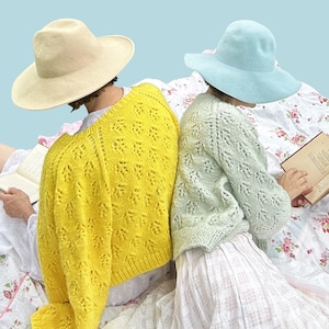 Könnte beinhalten: Zwei Personen mit Strickpullovern und breitkrempigen Hüten sitzen im Freien. Der eine Pullover ist leuchtend gelb, der andere hellgrün. Das Wort "PATTERN" wird in einem weißen Rechteck oben im Bild angezeigt. Sie lesen Bücher.