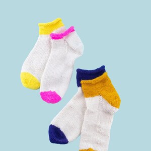 May include: White knit socks with colorful accents. One pair has yellow cuffs and toes, the other has pink cuffs and toes. A third pair has blue cuffs and toes, and a yellow stripe. The word "PATTERN" is in a white rectangle at the top.