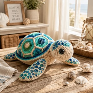Puede incluir: Un peluche de tortuga marina tejido a ganchillo con un caparazón de patrones hexagonales azules, turquesas y verdes. La cabeza y las aletas están hechas de hilo color crema con detalles en azul y turquesa. La tortuga tiene grandes ojos redondos de plástico negro.
