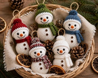May include: Five crocheted snowman ornaments with round bodies, orange noses, and black eyes. Each snowman wears a different colored hat and scarf, including red, green, blue, and white, with small brown buttons on the front and a jute hanging loop.