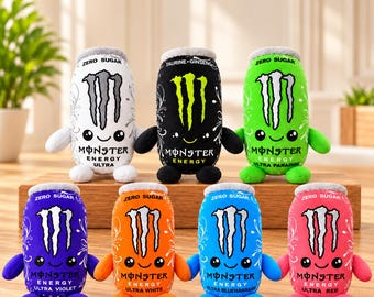 Puede incluir: Siete peluches con forma de latas de Monster Energy en blanco, negro, verde, morado, naranja, azul y rosa. Cada uno presenta el logo de Monster, una cara sonriente, brazos y pies pequeños. El texto KIDDS COLLECTIONS aparece en la parte superior.