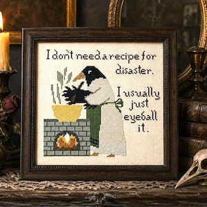 Peut inclure: Une broderie au point de croix encadrée représentant un oiseau noir et blanc portant un tablier vert, remuant un bol jaune au-dessus d'une cheminée en briques. Le texte indique : I don't need a recipe for disaster. I usually just eyeball it.