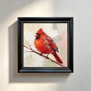 May include: An oil painting of a bright red cardinal bird perched on a thin brown branch. The bird has a black mask around its beak and is set against a soft, textured background of muted cream, pink, and green tones, framed in a black frame.