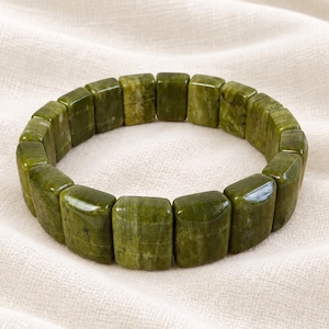 May include: A stretch bracelet composed of rectangular, polished olive green stone beads. The beads feature natural variations in colour and texture, arranged in a continuous circular loop to form a flexible band that fits around the wrist.