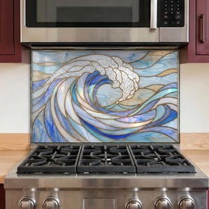 May include: A rectangular kitchen backsplash panel featuring a stained glass style design of a large crashing ocean wave. The artwork displays swirling shades of blue, white, and gold, with distinct leaded lines separating the glass segments.