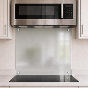 May include: A rectangular, light gray glass kitchen backsplash panel mounted with four silver circular hardware fasteners. The panel is positioned vertically between a stainless steel over-the-range microwave and a black glass induction cooktop.