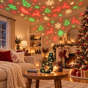 May include: A holiday light projector casting red and green laser patterns of Christmas trees, reindeer, snowflakes, and gift boxes onto the ceiling and walls of a living room decorated with a lit Christmas tree and fireplace.