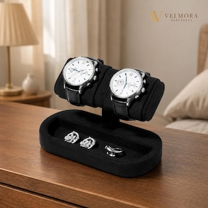 May include: A black velvet jewelry display stand featuring two silver-toned wristwatches with white faces and black leather straps mounted on a horizontal bar, with two silver earrings and a silver ring resting in the oval base tray below.