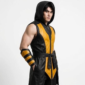 May include: A sleeveless black and yellow hooded vest featuring a front zip closure and a matching tie-waist belt. The garment is paired with a black and yellow forearm guard, creating a coordinated set with a distinct colour-blocked design.